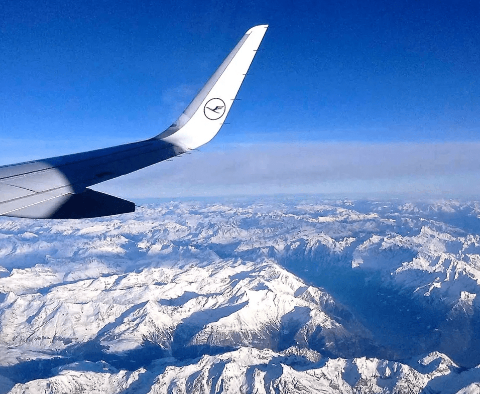 A view of the wing of an airplane flying over mountains.