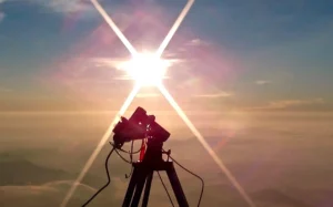 A camera and light spectrometer recording the sunrise on a mountain top. The spectral quality of daylight early in the morning has more red colors in the spectrum and therefore has low CCT values – under 3500K.