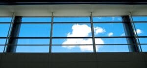 A large window high up in an airport showing blue sky and clouds. Humans prefer natural light that contains the full daylight spectrum.